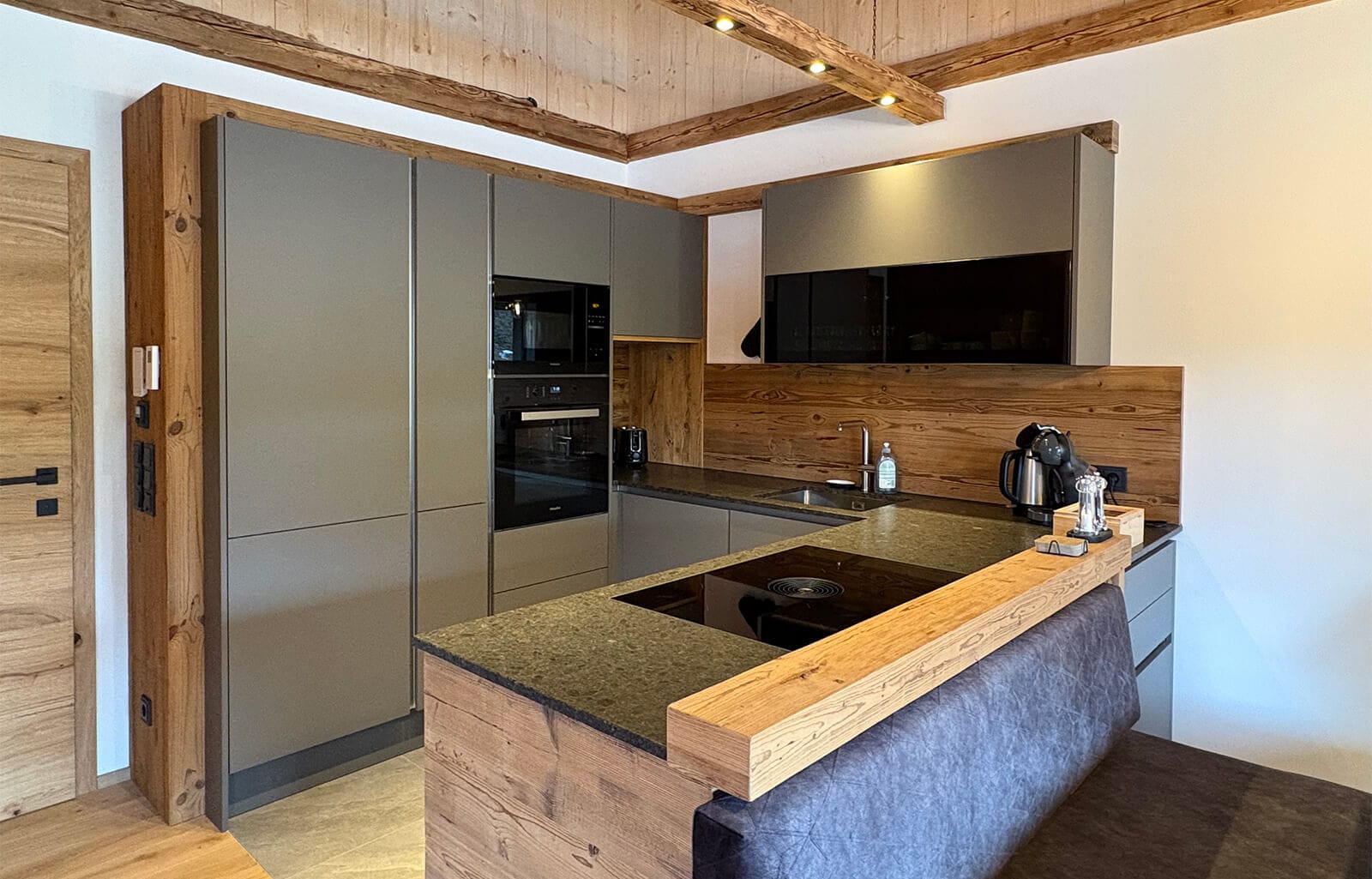 Moderne, minimalistische Küche im Apartment Bischofsmütze mit hochwertigen Einbaugeräten, dunkler Arbeitsplatte und viel Stauraum in hellem Naturholz-Design.